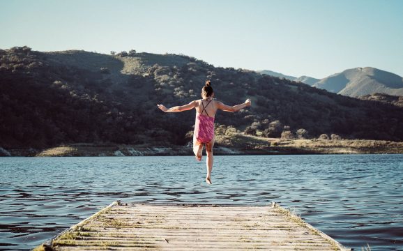 Girl jumping off dock into lake