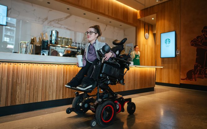 Woman in power wheelchair moves past Starbucks counter
