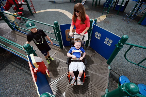 Suzanne Sullivan pushes her son Dermot, 8, across the walkway in his wheelchair at a playground in Hopkins, Minn. Dermot has a mitochondrial disorder but is able to play with his two brothers at the inclusive playground. (Jerry Holt/Minneapolis Star Tribune/MCT)