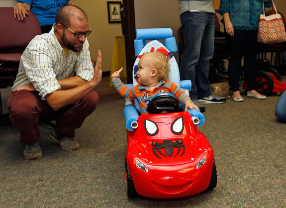 Christopher Roe high-fives Go Baby Go workshop leader Sam Logan in his newly modified Fisher-Price Power Wheels Lil' Lightning McQueen. (Kyle Robertson/Columbus Dispatch/MCT)